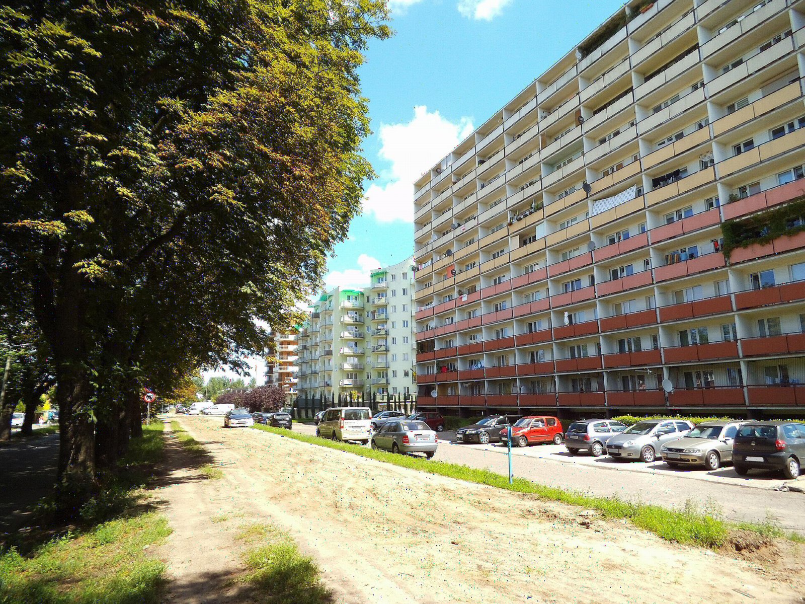 Pas dawnego torowiska linii Toruń - Czarnowo obok wysokich bloków mieszkalnych w Toruniu